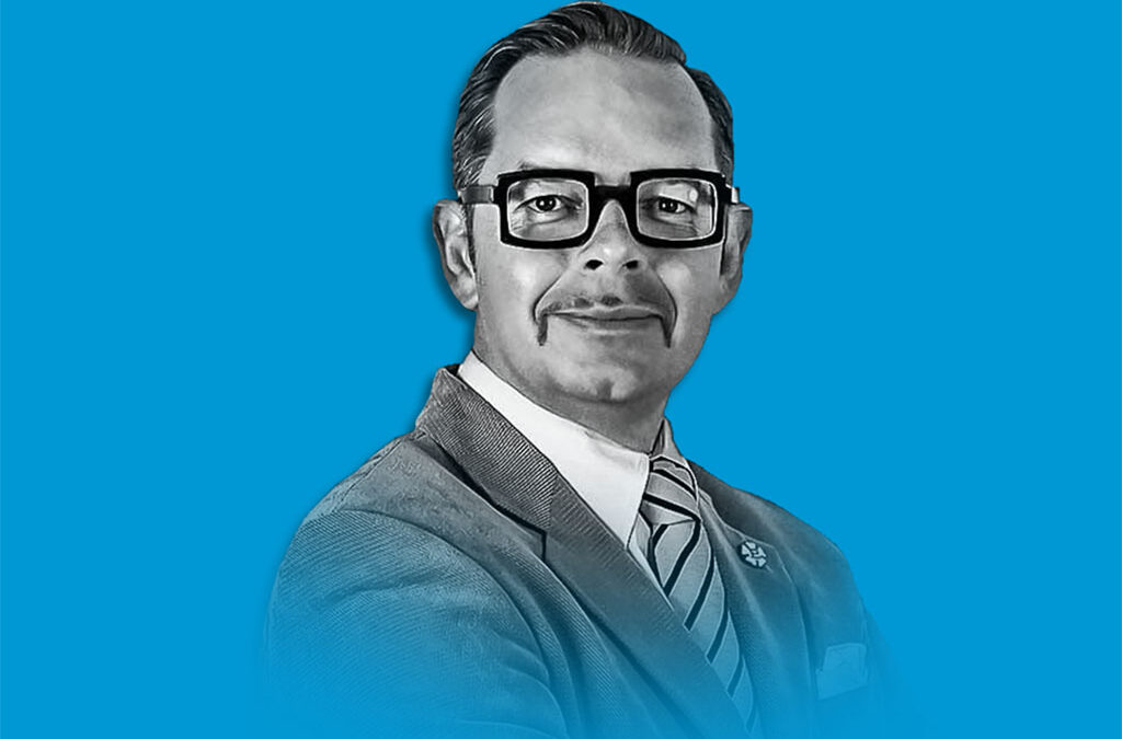 En man i kostym på blå bakgrund.