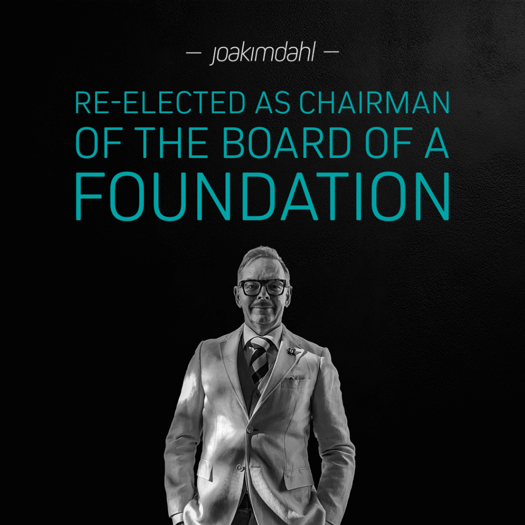Re-elected chairman of the board of a foundation, wearing a suit and glasses, standing confidently against a dark background.