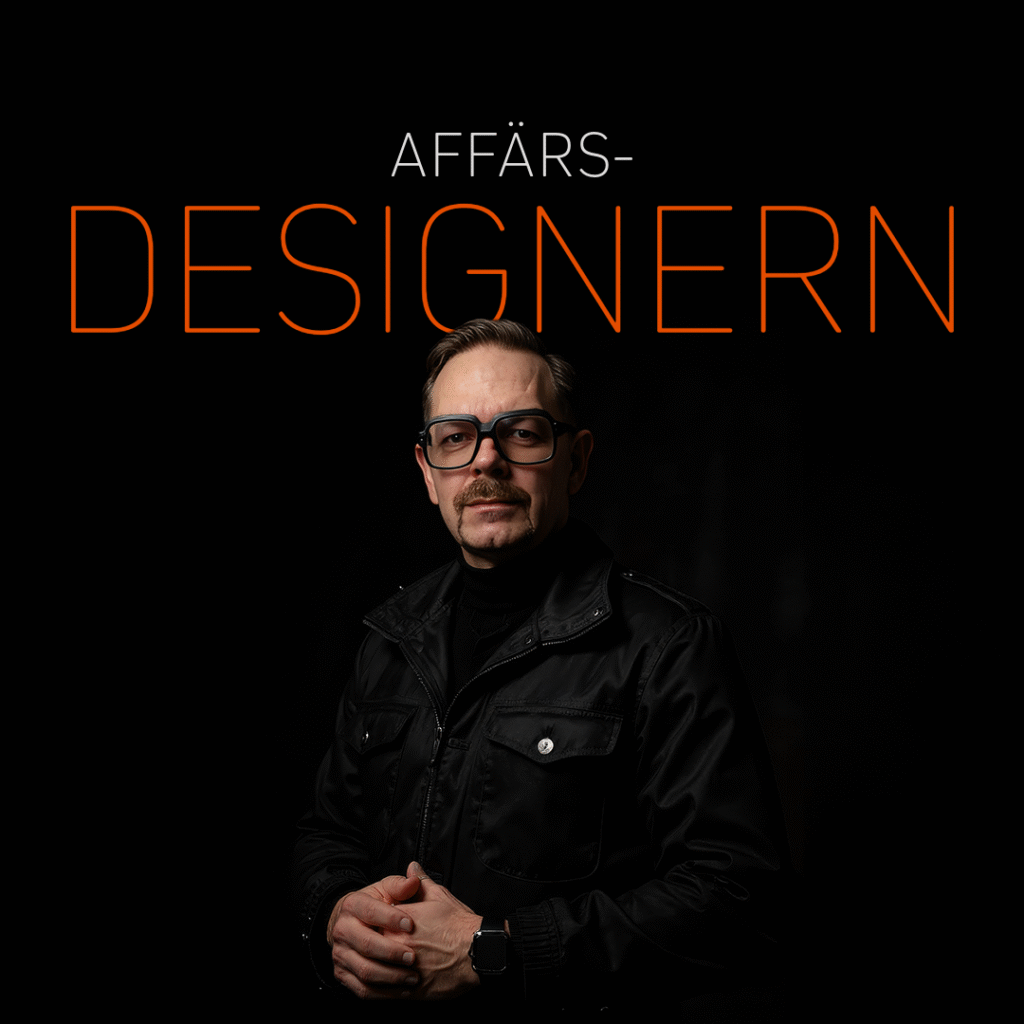 Affärsdesigner i svart jacka med glasögon, poserar med händerna ihop i en mörk miljö.