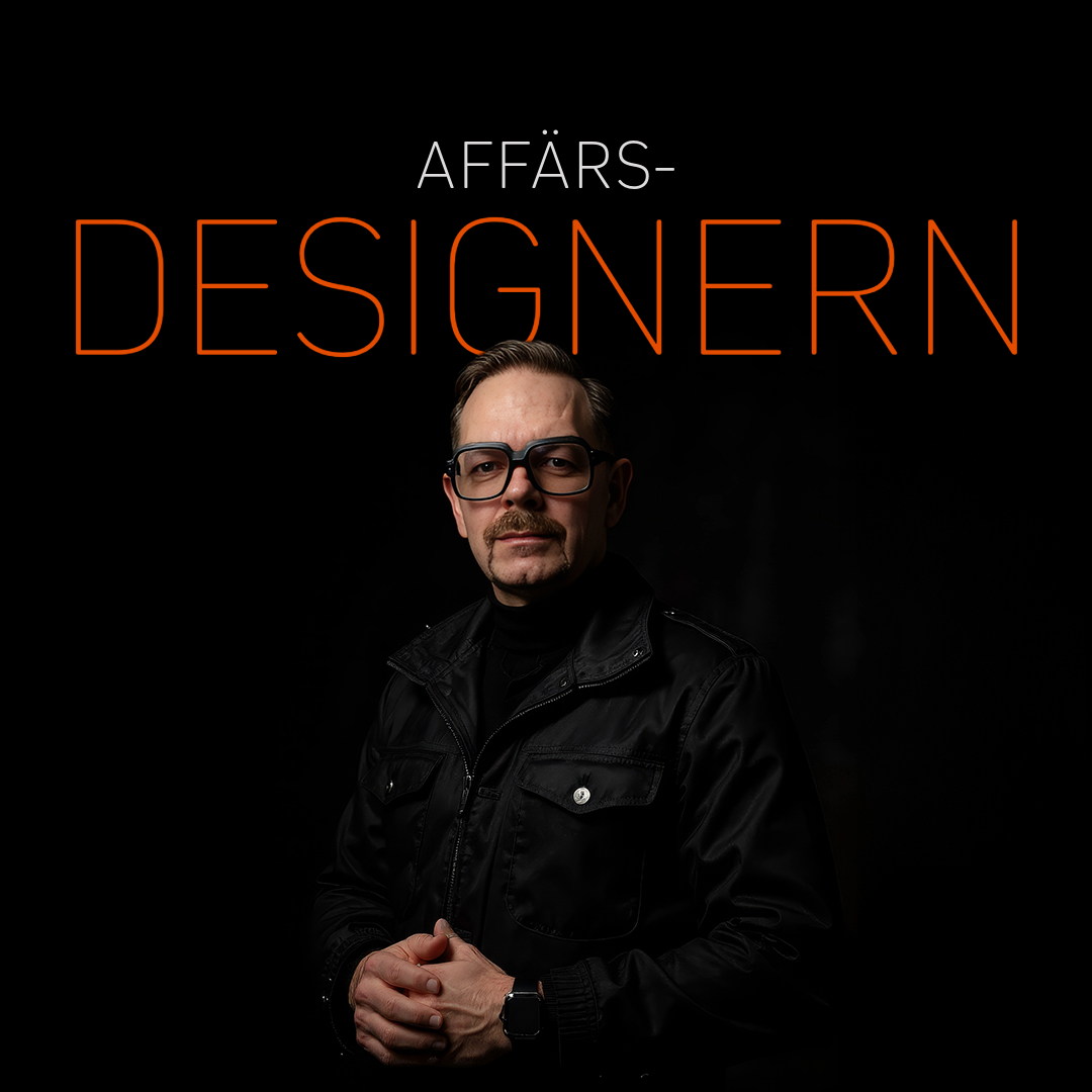 Affärsdesigner i svart jacka med glasögon, poserar med händerna ihop i en mörk miljö.