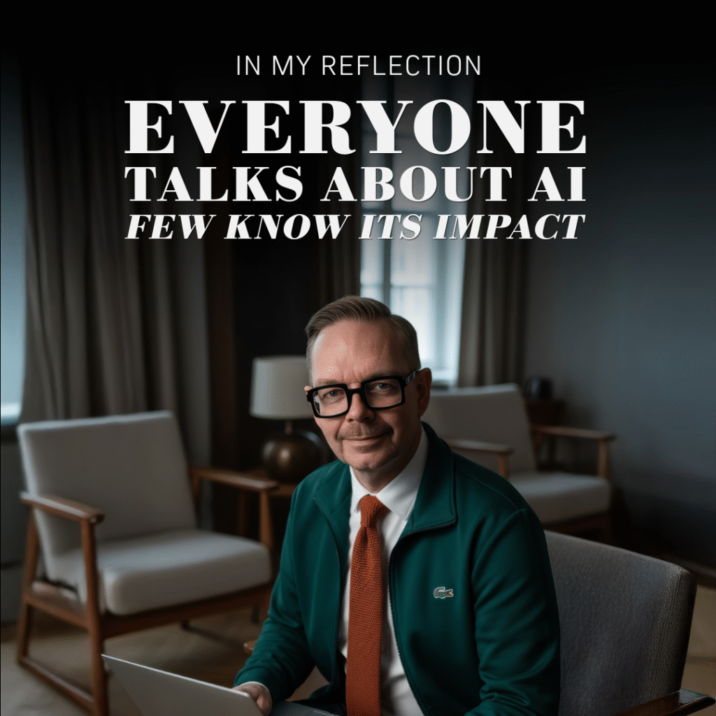 Man i grön jacka och glasögon sitter med en laptop i en kontorsmiljö.