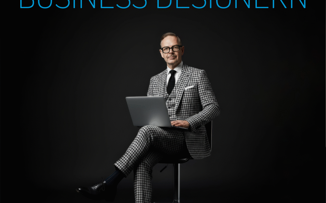 Man i rutigt kostym sitter på en stol med en bärbar dator i knät.