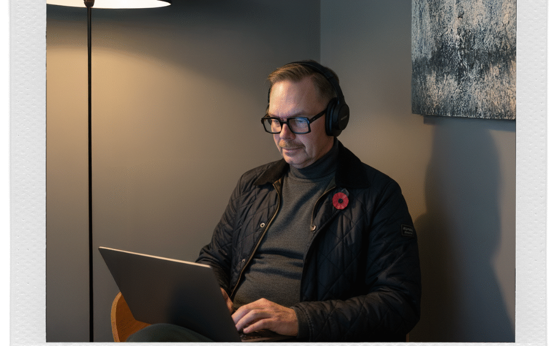 Man med hörlurar som arbetar på en laptop i en inbjudande miljö med mjukt ljus.