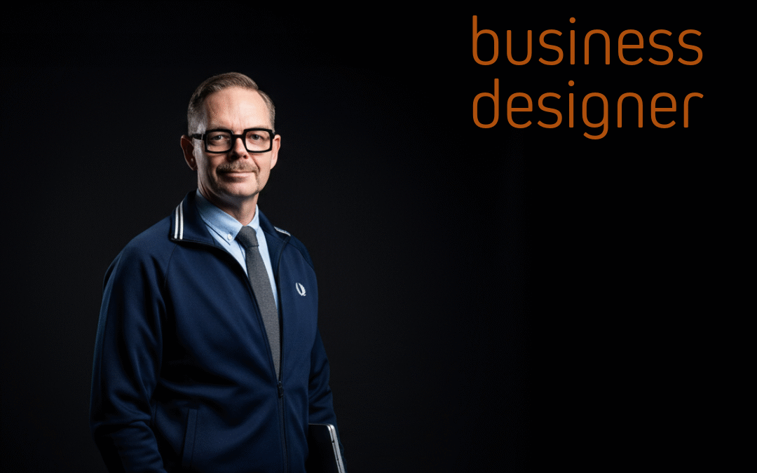 Affärsdesigner i mörkblå jacka med vit krage, står med en laptop i handen, mot en svart bakgrund.