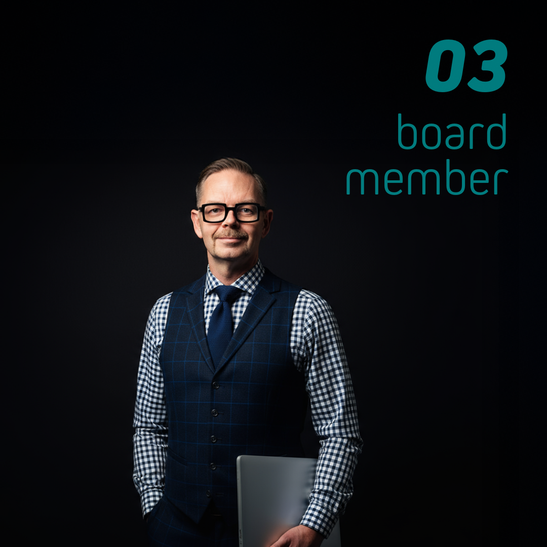 En man i väst och skjorta med glasögon, som står med en laptop i handen och har ett neutralt uttryck.