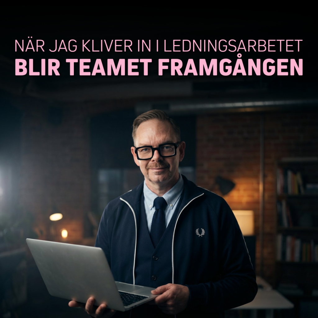 Man med glasögon och laptop i handen, klädd i mörkblå tröja och vit skjorta, står i ett kontorsrum.