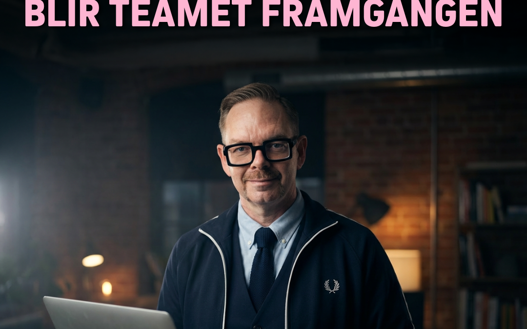 Man med glasögon och laptop i handen, klädd i mörkblå tröja och vit skjorta, står i ett kontorsrum.