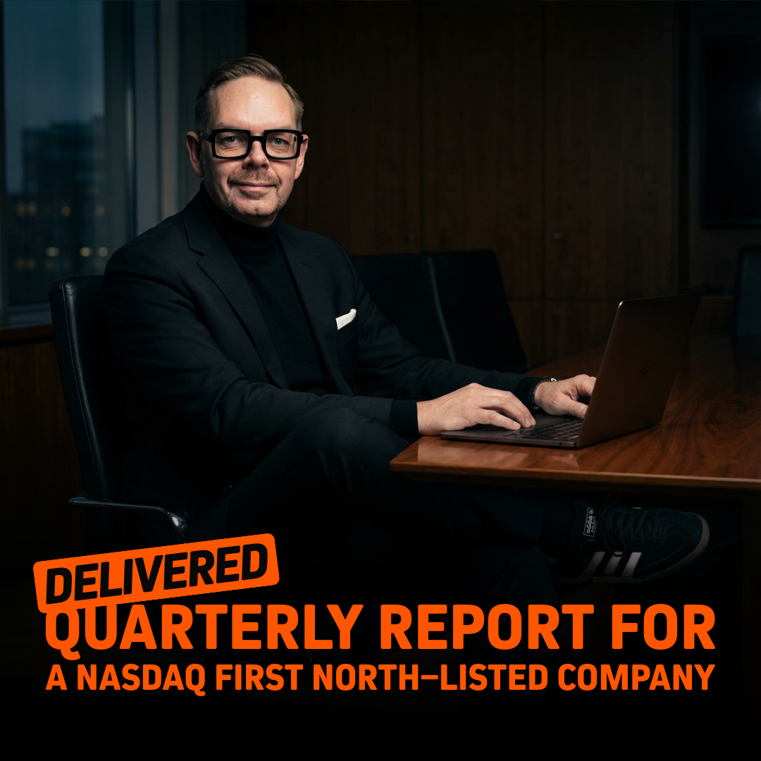 Man i kostym som sitter vid ett bord och arbetar med en laptop, med en kvartalsrapport för ett Nasdaq First North-noterat företag.