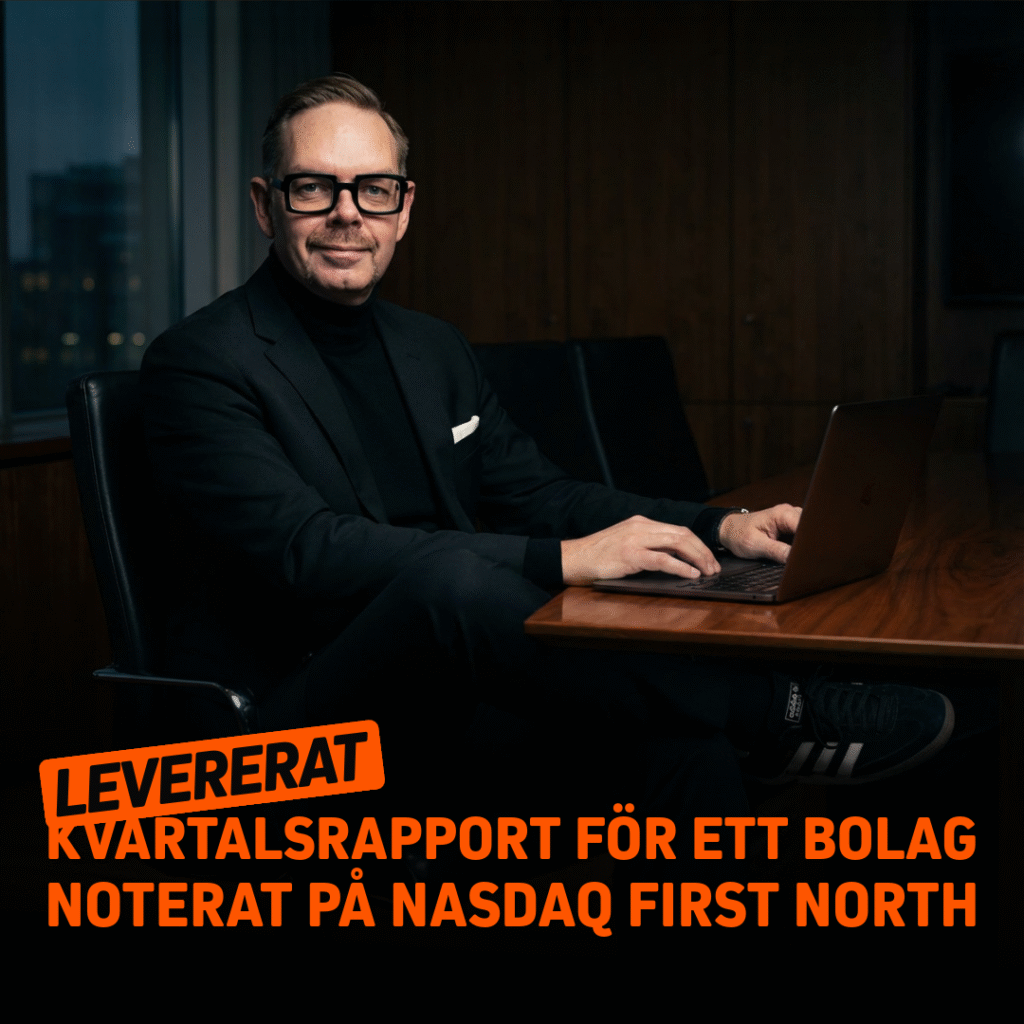 Man i svart kostym och glasögon som arbetar vid en laptop i en modern kontorsmiljö.