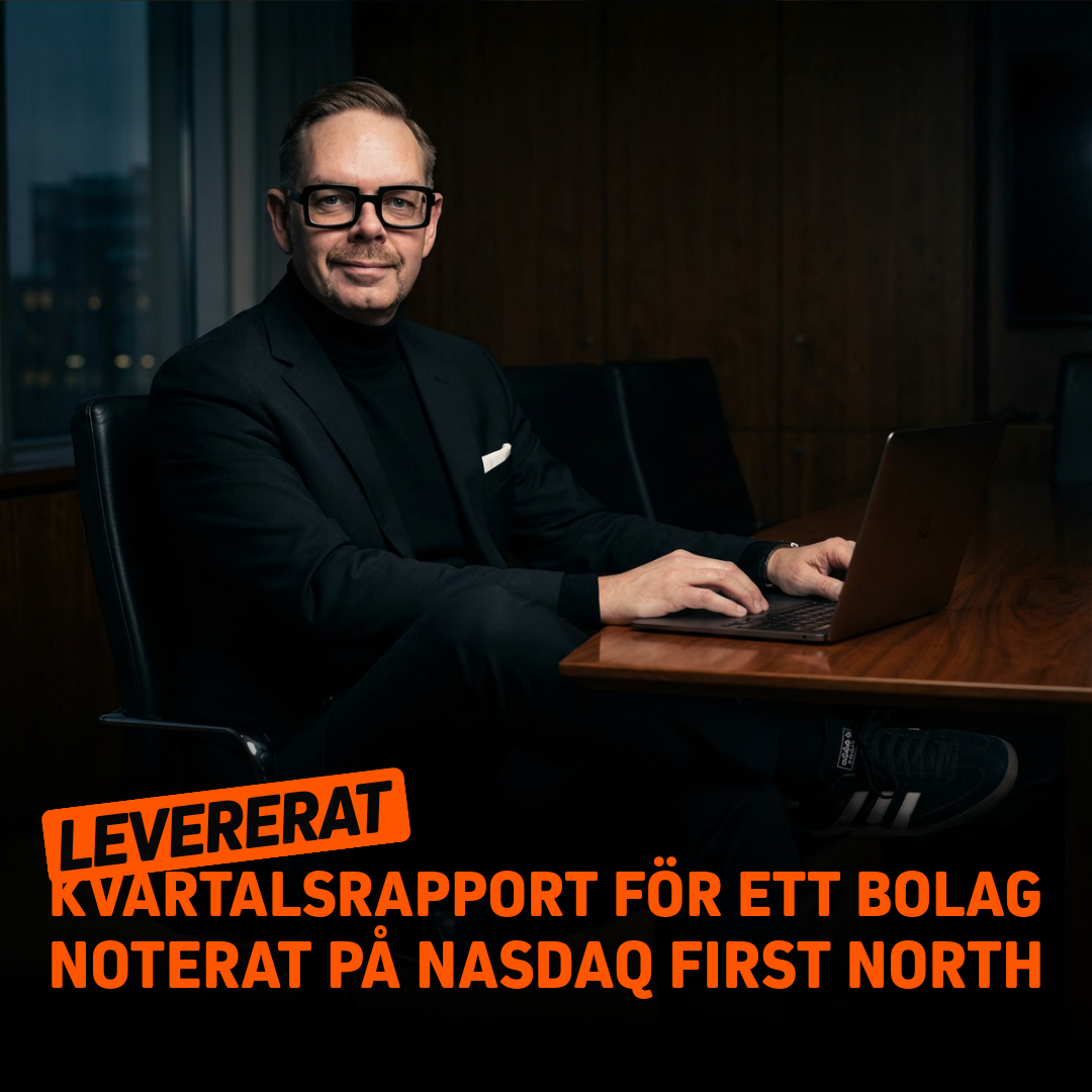 Man i svart kostym och glasögon som arbetar vid en laptop i en modern kontorsmiljö.