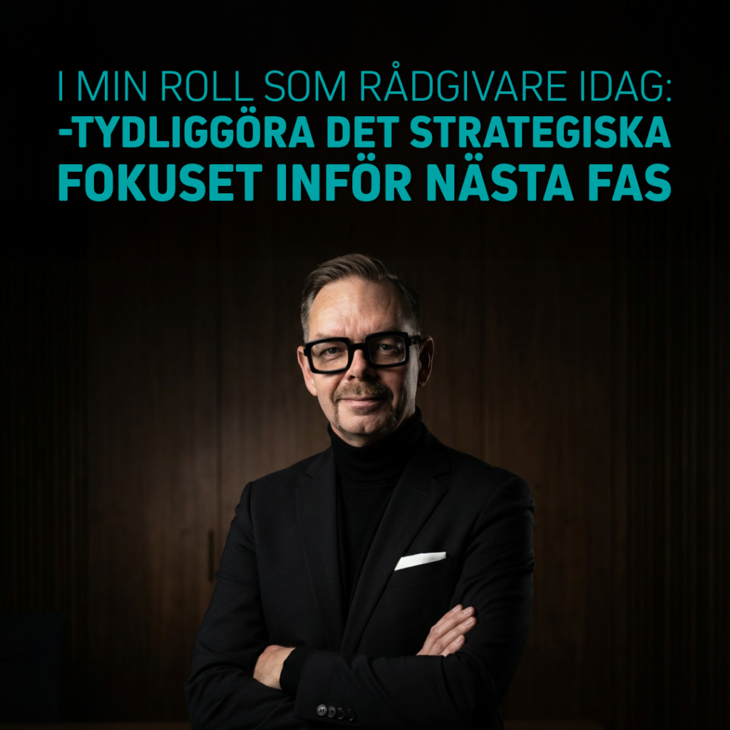 Man i svart kavaj och glasögon står med armarna i kors och ler mot kameran.