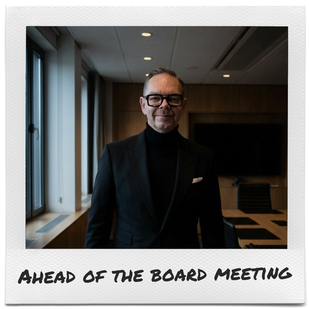 Joakim Dahl i svart kostym och svarta glasögon står i ett modernt konferensrum med stora fönster; polerat trä och dämpad belysning ger en professionell atmosfär, text synlig i polaroidramen.